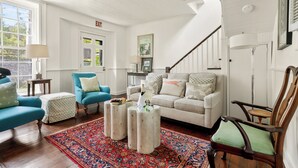 Una sala de estar con un sofá, sillones, una mesa de centro y una alfombra estampada.