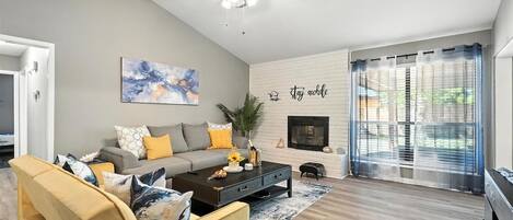 A living room with a sofa, coffee table, and a fireplace.