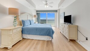 A bedroom with a bed, a dresser, a television, and a ceiling fan.