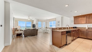 A spacious living area with a kitchen, dining table, and a view of the outdoors.
