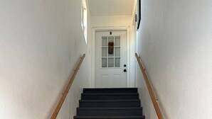 A staircase with wooden handrails leading to a white door marked with the letter 'B'.