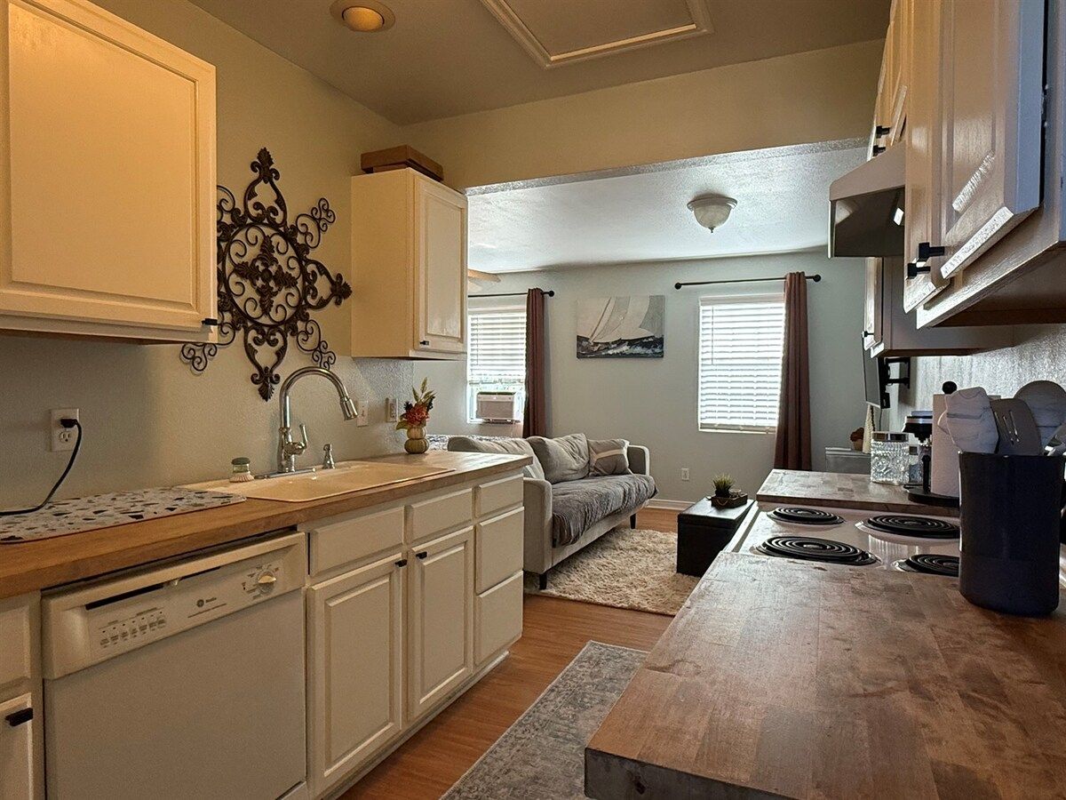 A compact kitchen with white cabinetry, a built-in dishwasher, and a central island with a sink.