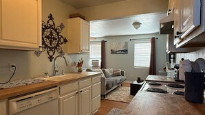 A compact kitchen with white cabinetry, a built-in dishwasher, and a central island with a sink.