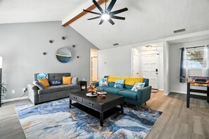 Un salon avec un canapé, une table basse et un ventilateur de plafond.