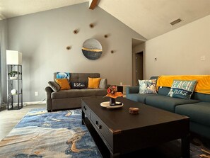 A living room with a sofa, a coffee table, and a rug. - The Inland Tide 3 bedrooms • 2 bath  • Entire home (Abilene)