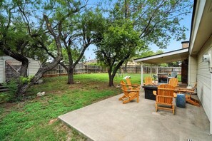 Un jardin avec un patio couvert, un espace salon extérieur, un barbecue et une cour clôturée.