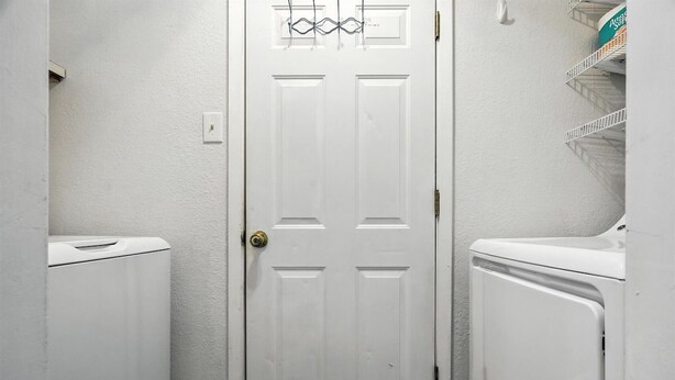 A white door with a simple design, flanked by two white appliances, likely a washer and dryer, in a small, enclosed space. - The Inland Tide 3 bedrooms • 2 bath  • Entire home (Abilene)