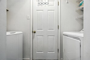A white door with a simple design, flanked by two white appliances, likely a washer and dryer, in a small, enclosed space. - The Inland Tide 3 bedrooms • 2 bath  • Entire home (Abilene)