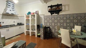 A kitchen with white cabinets, a built-in stove, and a dining area with a glass table and chairs. - Charming Traditional Apartment – Calm & Cozy, Near Marrakech Airport (Marrakesh)