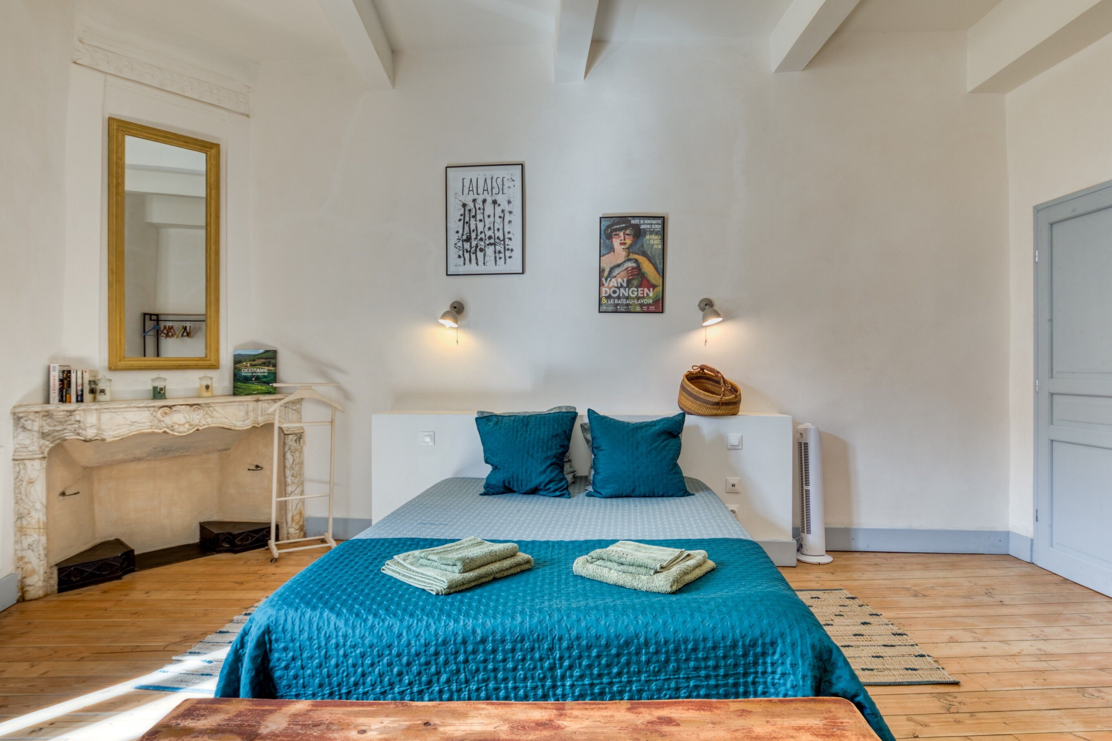 A bedroom with a bed, a vanity with a mirror, and two wall-mounted lamps.
