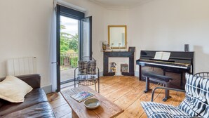Un soggiorno con un pianoforte, un divano, un tavolino da caffè e un camino.