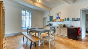 Une cuisine spacieuse avec un plancher en bois, une table à manger avec des chaises, un banc, un lave-vaisselle et une fenêtre donnant sur un beau paysage.
