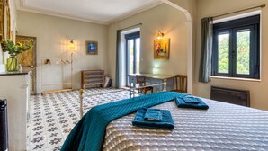 Une chambre à coucher comprenant un lit, un bureau, une chaise, une commode et une fenêtre avec des rideaux.