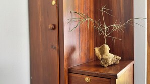 A wooden cabinet with a drawer and a small plant in a rock-like pot.