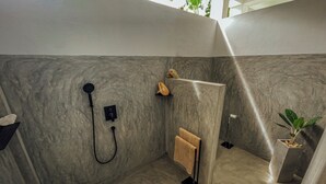 Una ducha moderna con cabezal de ducha manual y panel de control en la pared.