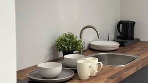 A modern kitchen with a wooden countertop, a sink, a coffee maker, and a potted plant.