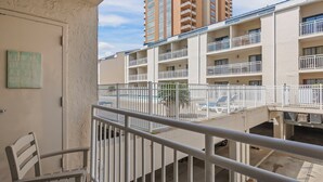 Een meerlaags appartementencomplex met balkons, een zwembad en een uitzicht op hogere gebouwen op de achtergrond.