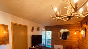 Un interior acogedor de cabaña con una mesa de comedor de madera, un televisor y una lámpara del techo.
