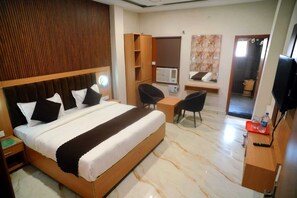 Una habitación de hotel con una cama grande, un escritorio, una silla, un televisor y un armario.