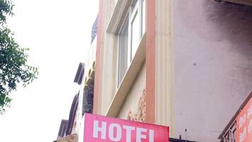 A red sign advertising 'HOTEL DIVINE STAY' with 'AC ROOMS AVAILABLE' and a contact number.