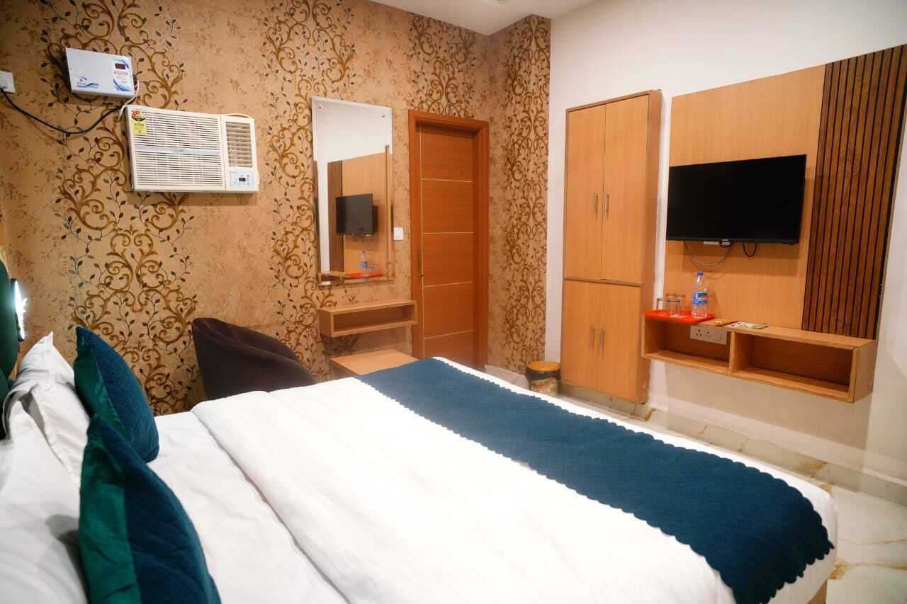 Camera d'albergo con un letto, una TV a parete, un armadio e uno specchio.
