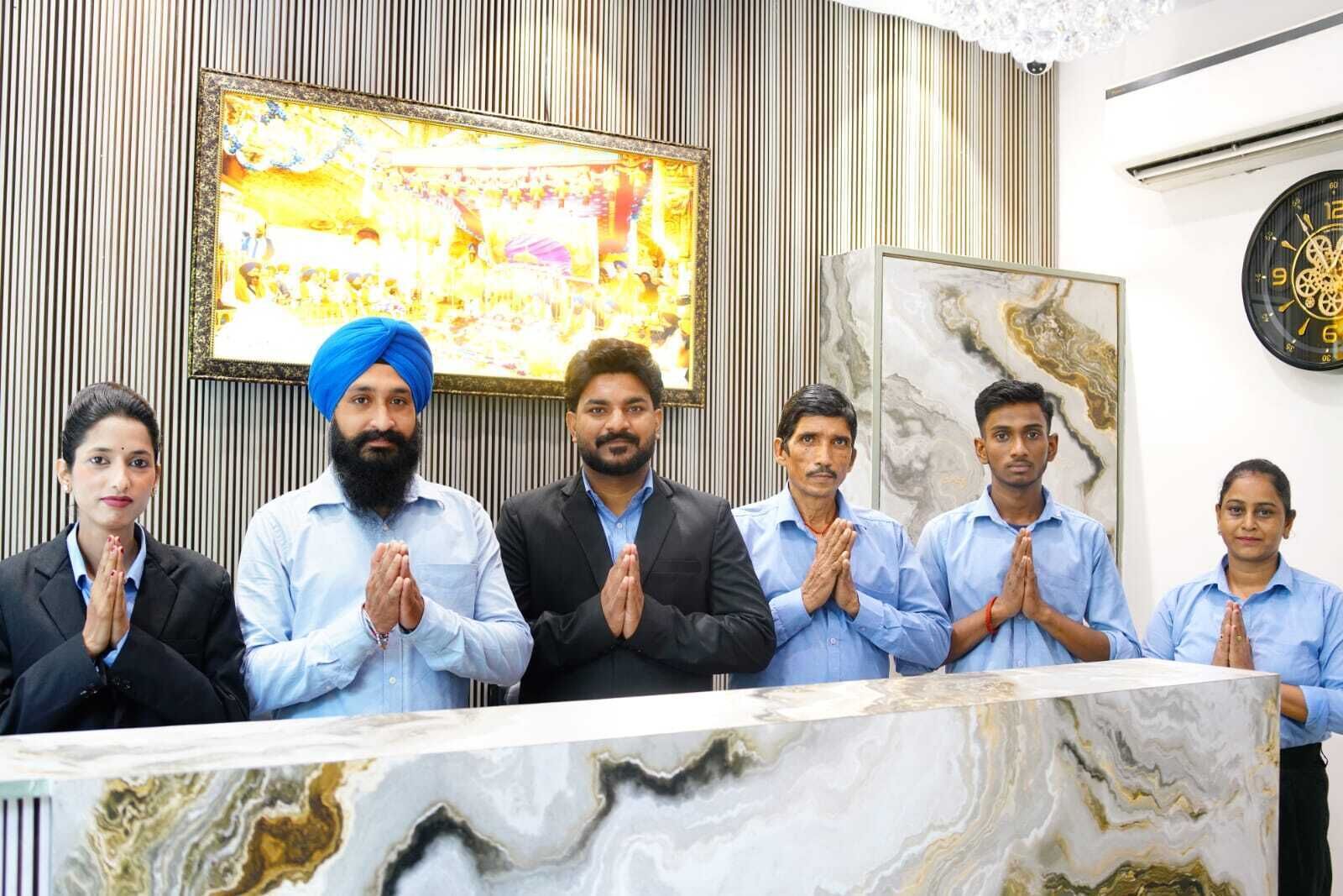 A group of people standing in a reception area with a marble reception desk, a framed artwork on the wall, and a clock.