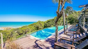 A poolside area with a view of the ocean, wooden deck, and lounge chairs. - Azumi Yutori Beach House Sunrise (Agnes Water)