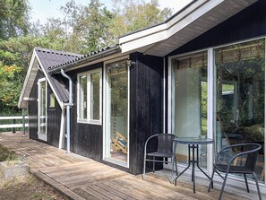 Una terraza de madera con un ventanal de vidrio que da a un espacio exterior cubierto.
