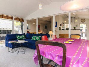 A room with a blue sofa, a dining table with a pink tablecloth, and a view of the outside.