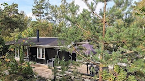A cabin with a deck, surrounded by dense trees. - 6 Person Holiday Home in Stege (Stege)