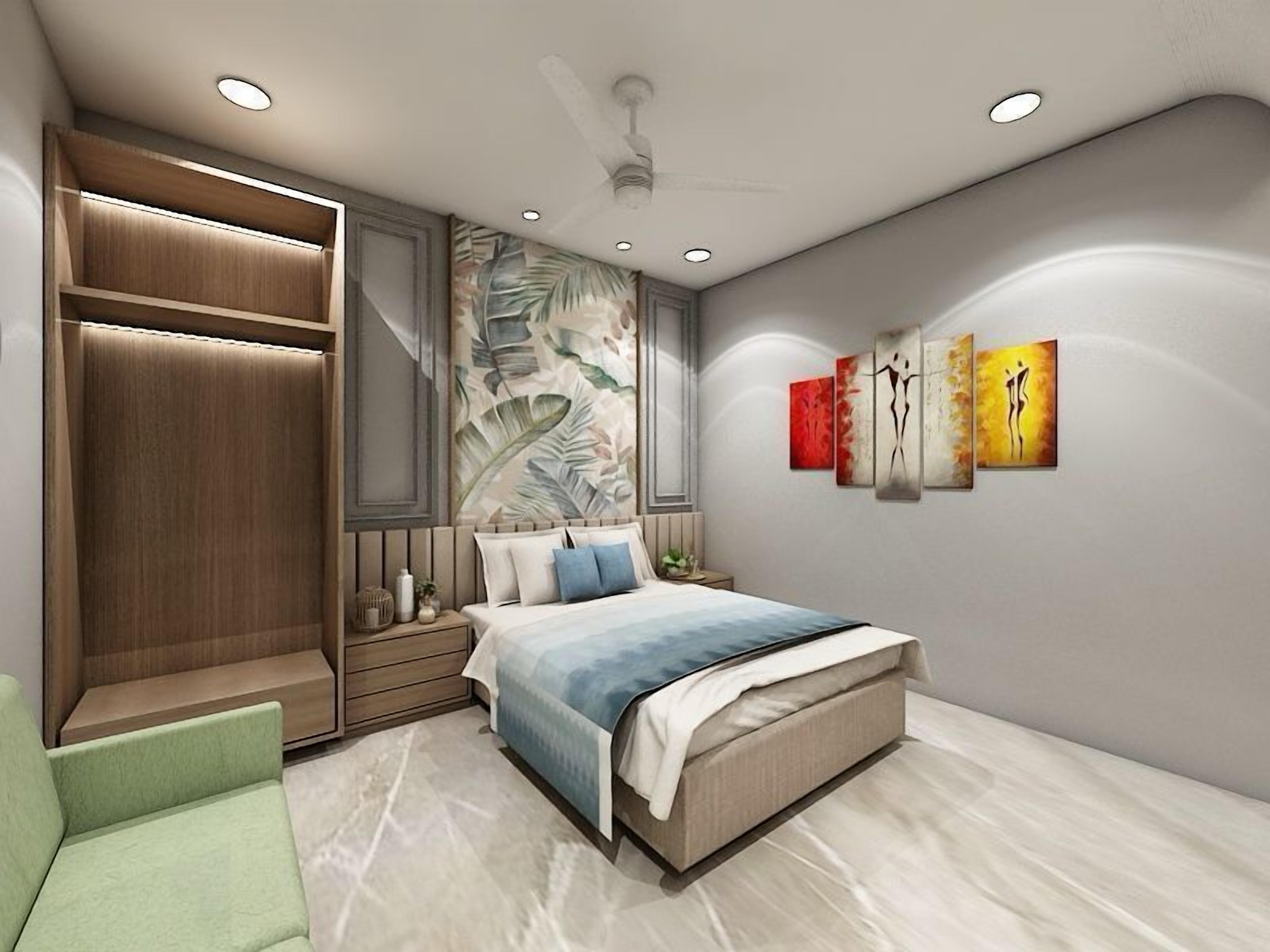 A modern bedroom with a bed, a green chair, a wardrobe, and artwork on the wall.