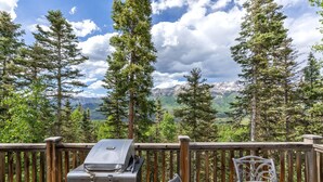 Ein Grill auf einer Holzterrasse mit Blick auf die Berge.