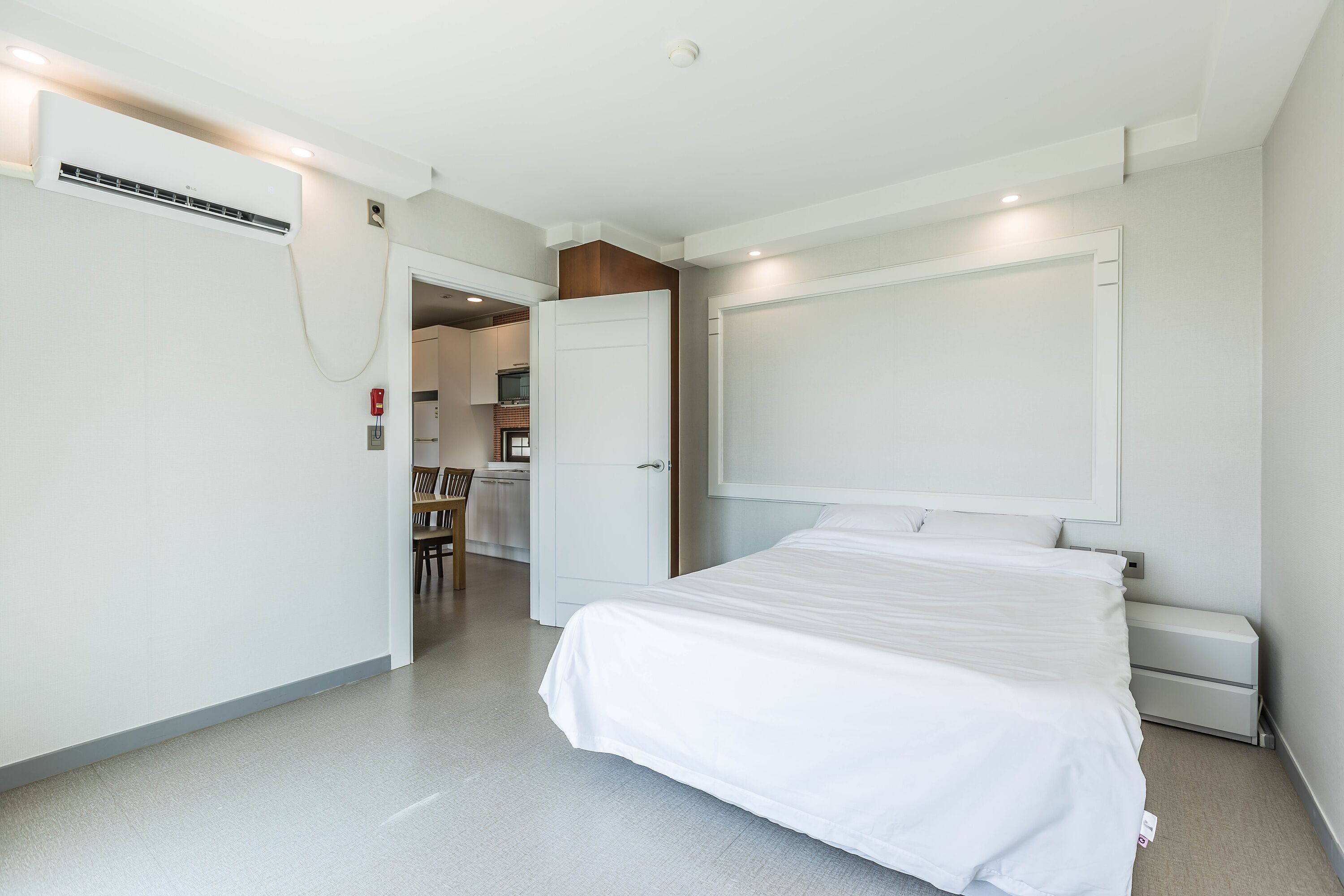 A modern hotel room with a large bed, a built-in desk, and a separate bathroom area.