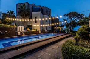 Um edifício moderno com piscina, luzes de corda e palmeiras.