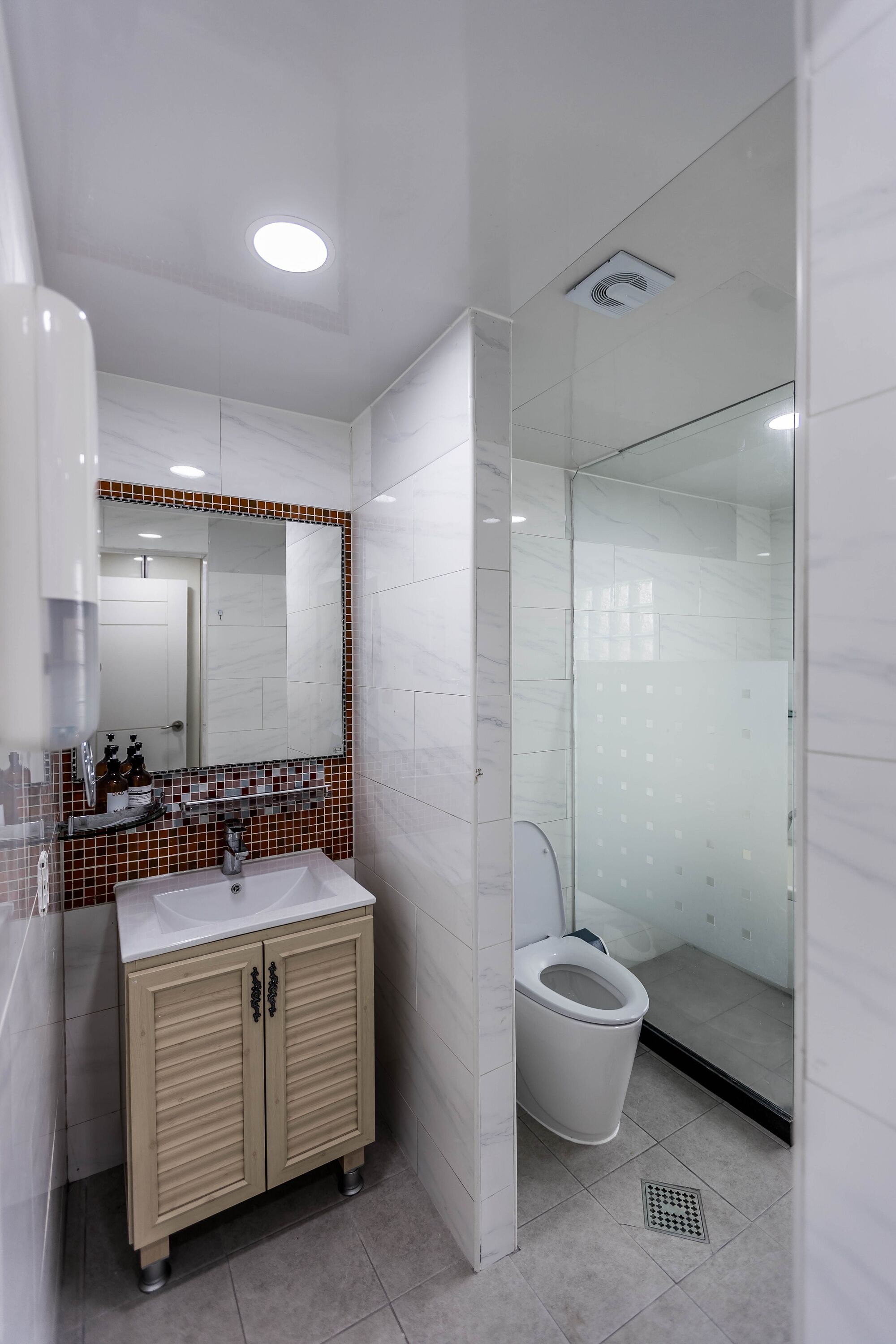 A modern bathroom with a marble vanity, a glass shower enclosure, and a white toilet.