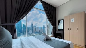 Een hotelkamer met een groot bed, een televisie, een kledingkast en uitzicht op een stadsbeeld.