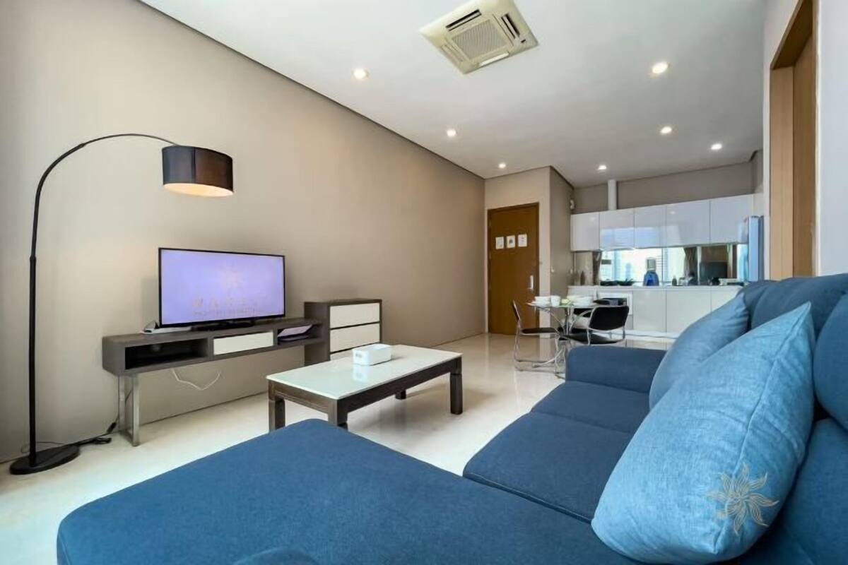 A modern living room with a sofa, a TV, a coffee table, and a lamp.
