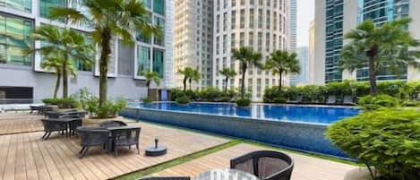 A rooftop patio with outdoor seating, a swimming pool, and high-rise buildings in the background.