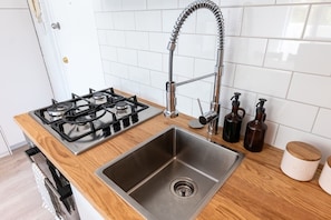 A kitchen with a stainless steel sink, a gas stove, and wooden countertops.
