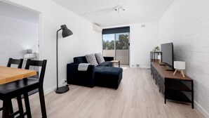 Un espacio habitable compacto con sofá, mesa de comedor y televisor.