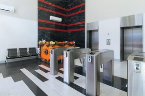 Un hall con mostrador de recepción, área de check-in, sala de espera y un ascensor.