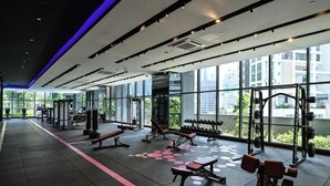 A gym with various exercise equipment, large windows, and a modern design.