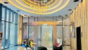 A modern lobby with a circular ceiling design, seating areas, and large windows.