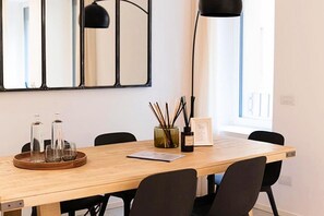 Una mesa de comedor con sillas, una bandeja con vasos y botellas, un cuadro enmarcado y un candelabro.