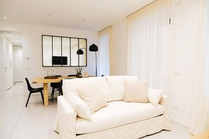 Una sala de estar moderna con un sofá blanco, una mesa de comedor y un espejo grande en la pared.