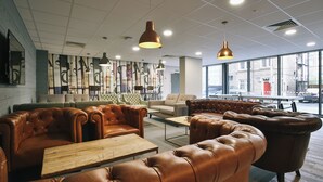 A modern lounge area with leather sofas, wooden tables, and pendant lighting. - Student Only Oldgate House (Huddersfield)