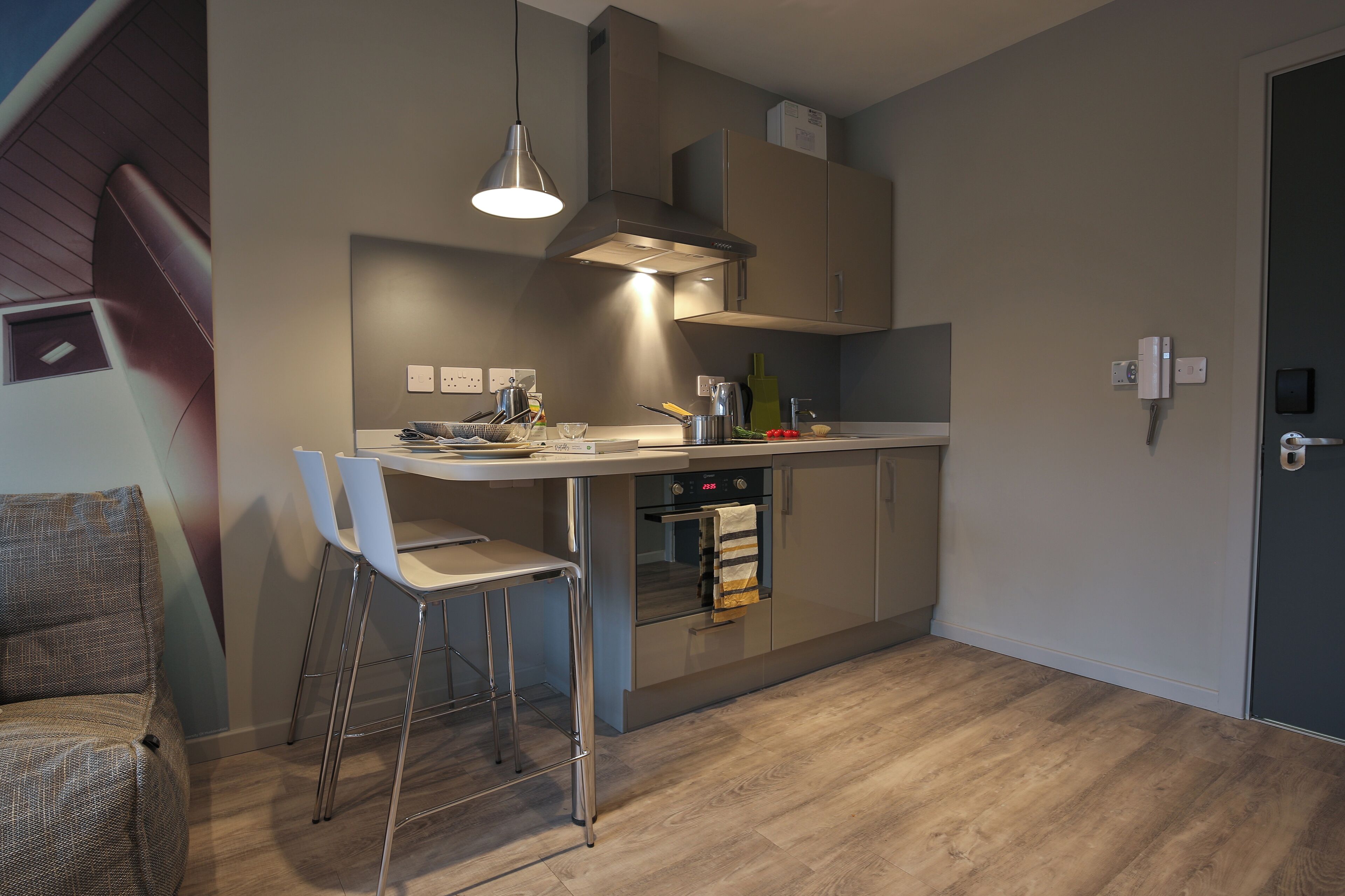 Eine moderne Küche mit Backofen, Edelstahl-Schränken und einem Barhocker.