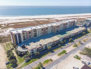 Ein großes Hotel mit mehreren Etagen, einem Parkplatz und Blick auf den Strand.