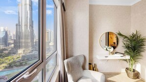 Ein modernes Zimmer mit einem großen Fenster, einem weißen Stuhl, einem runden Spiegel, einer kleinen weißen Ablagefläche und einer Topfpflanze.