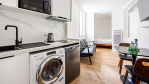 A modern kitchen with a built-in washing machine, a microwave, and a kettle.